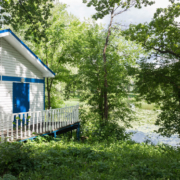 A lake home surrounded by vegetation overlooking the water.