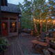 A beautiful outdoor deck with tasteful lighting outside of a lake home.