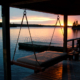A summer sunset over a boat dock on a lake, surrounded by a forest.