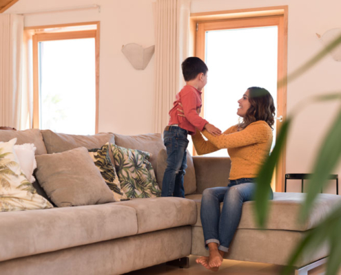 A woman sitting on the couch in the living room and playing with her son.