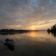 Sunset over a wooded lake with a boat dock.