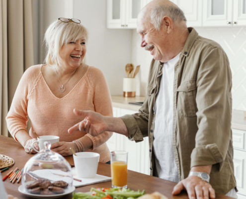 A couple of senior citizens standing in a kitchen for breakfast.