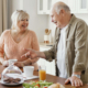 A couple of senior citizens standing in a kitchen for breakfast.