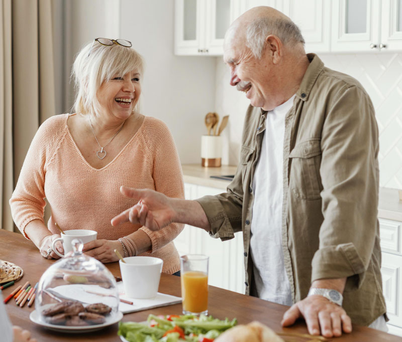 A couple of senior citizens standing in a kitchen for breakfast.