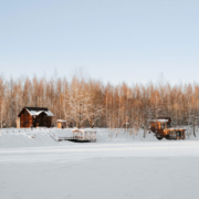 A group of lake homes viewed from a snow-covered frozen lake in winter.