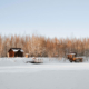 A group of lake homes viewed from a snow-covered frozen lake in winter.